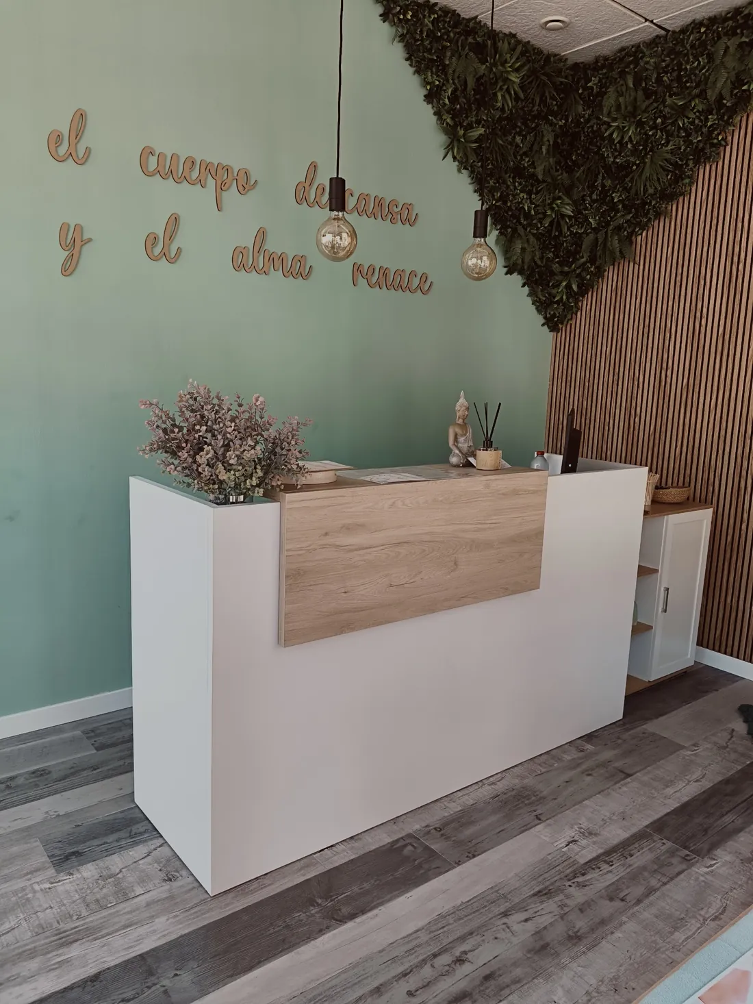 Recepción con la frase de madera en la pared verde y el mostrador iluminado